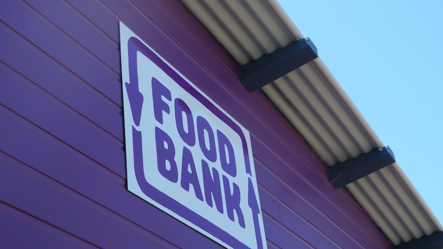 white and purple sign which says foodbank on purple wooded wall. 