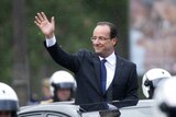 France's president Francois Hollande waves to the crowd as he parades in a car on the Champs-Elysee.