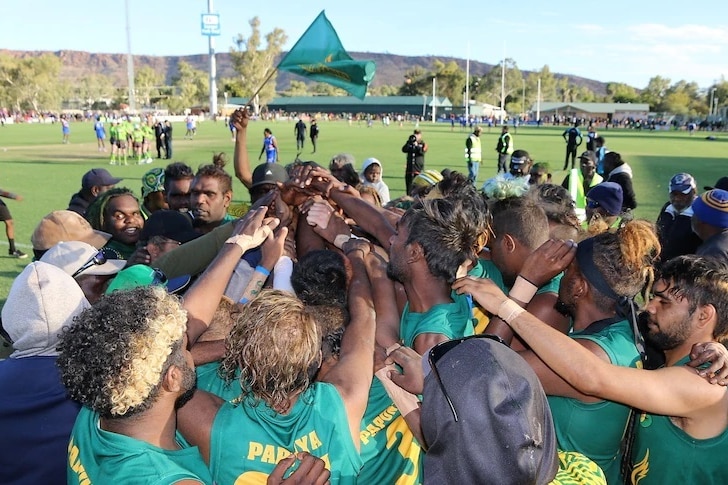 A community football team, wearing green and gold, celebrates a win.