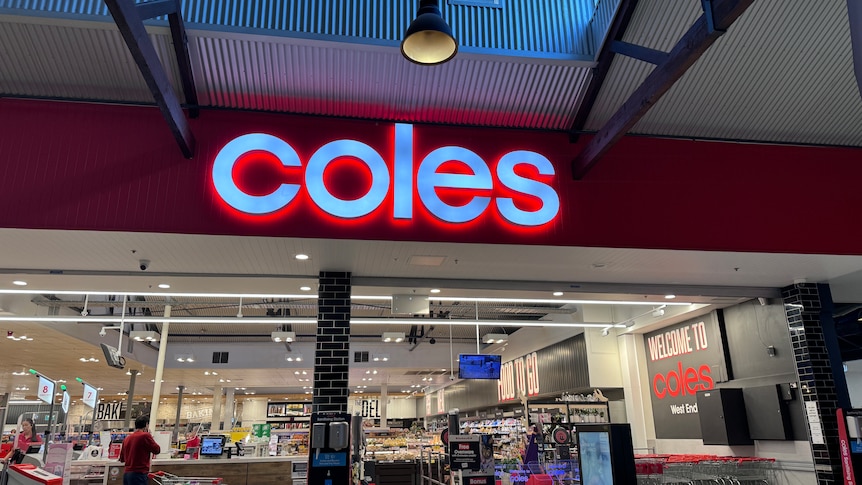 Red Coles sign lit up above entrance to a store