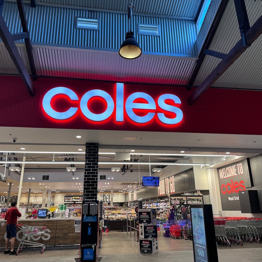 Red Coles sign lit up above entrance to a store
