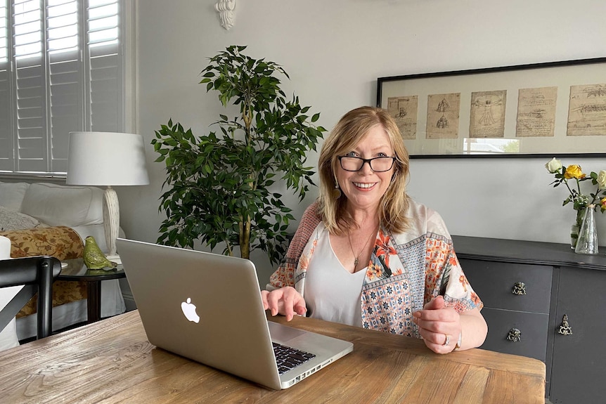 A woman sitting at a table with a laptop