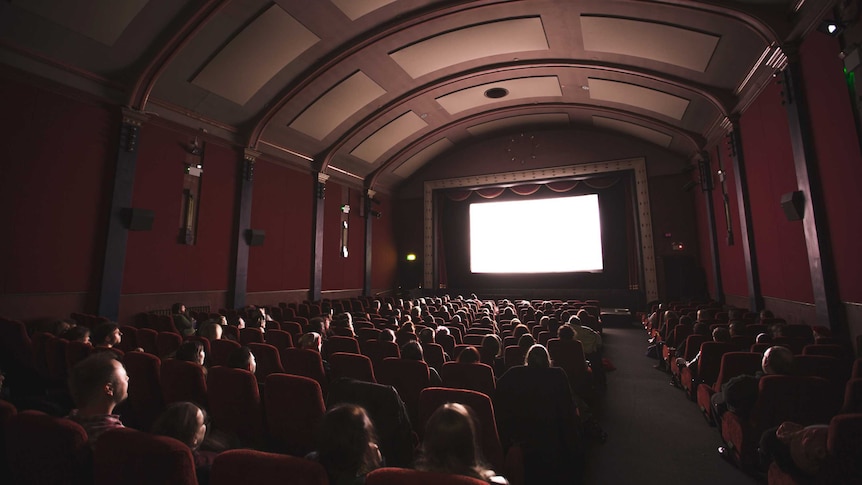 People sitting in a darkened movie theatre