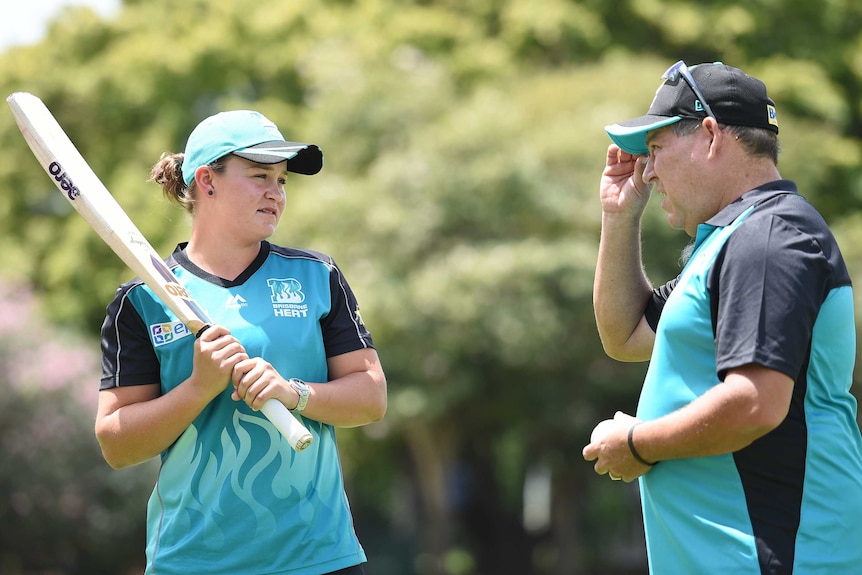 Ashleigh Barty holds a cricket bat as she looks at Brisbane Heat coach Andy Richards.