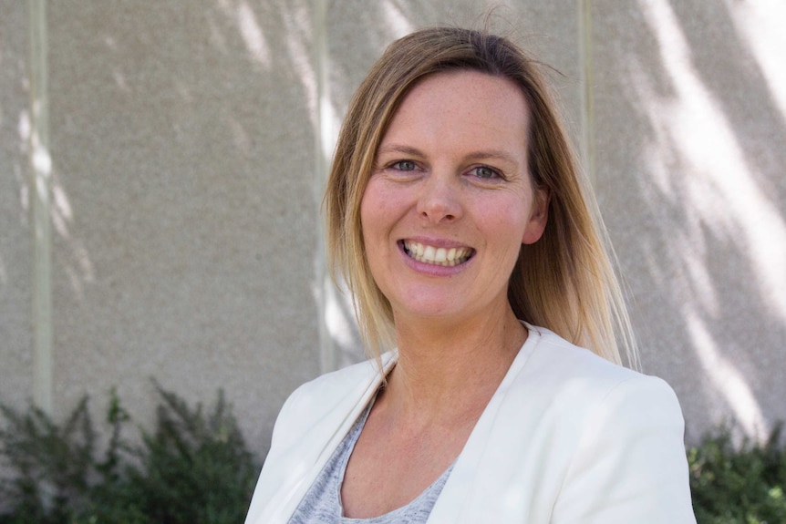 A portrait of Lisa Hester, smiling in a garden.