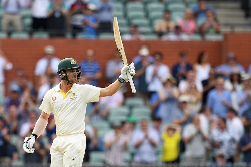 Australia batsman Travis Head points his bat skyward as the Adelaide Oval crowd watches on.