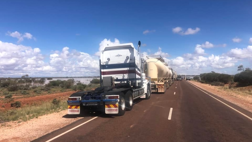 A photo of an outback highway with road trains parked on either side.