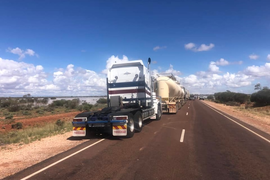 A photo of an outback highway with road trains parked on either side.