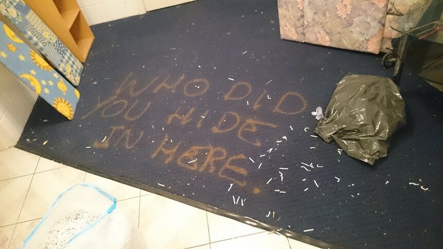 The words 'who did you hide in here' spray painted on the carpet.