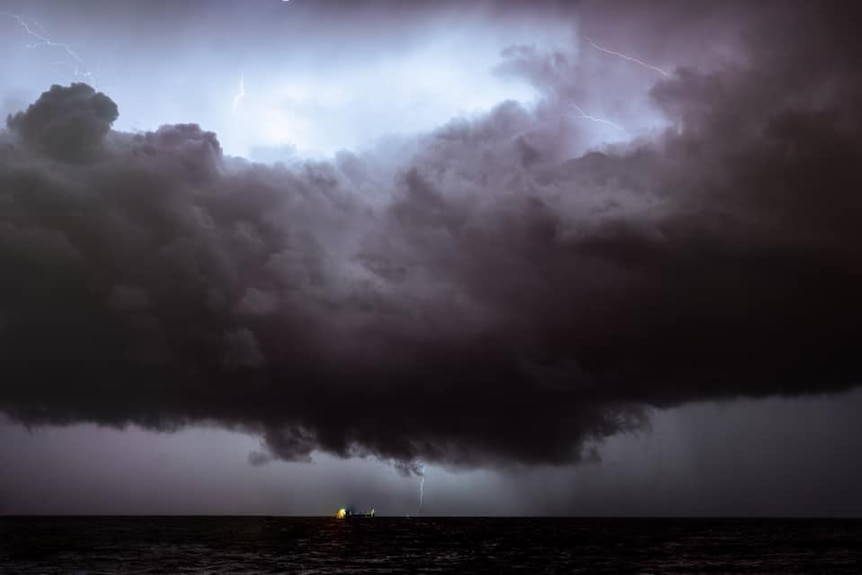 Oscuras nubes de tormenta y relámpagos en la distancia hasta el mar frente a Trig Beach.