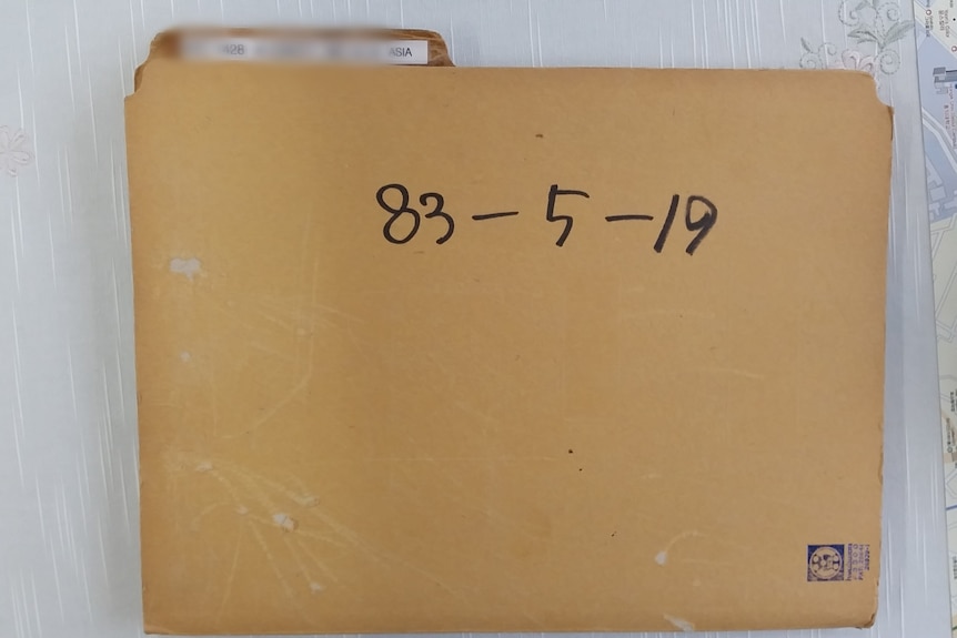 A yellow manila folder with some identifying information blurred out is seen with the dates 83-5-19 on it, a map is on the right