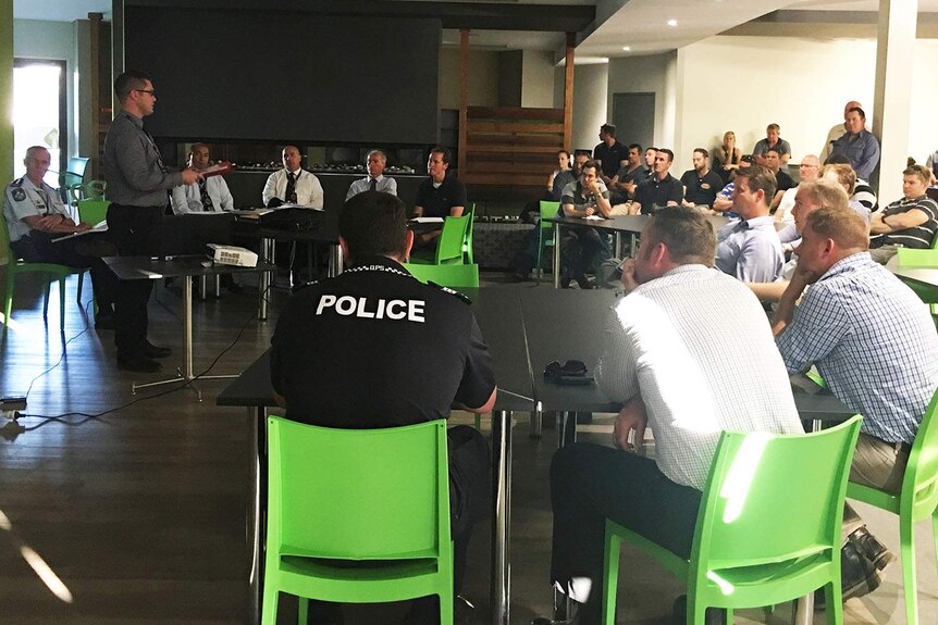 Police officers hold a meeting to discuss their drug raid operation