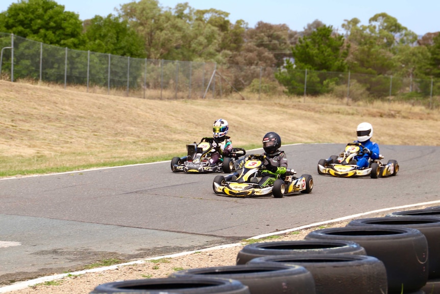 Three kids in karts on the track.