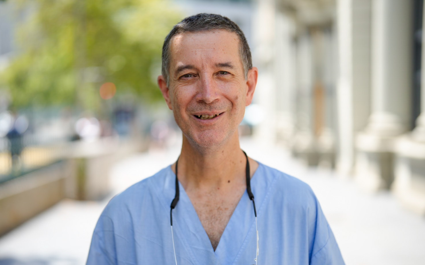 Anthony Grabs sonríe y viste una bata de hospital de color claro.