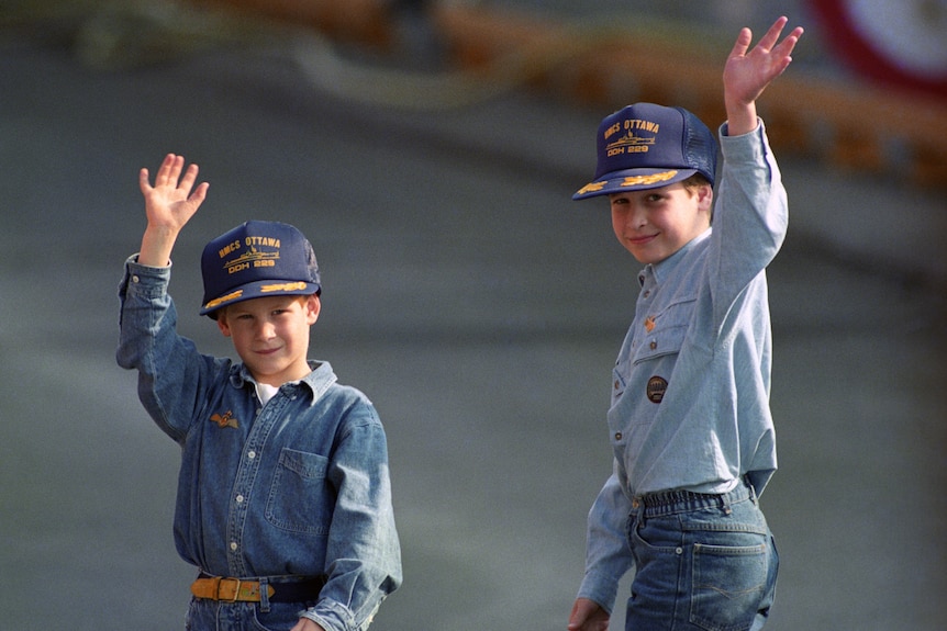 Two little boys in matching caps waving 