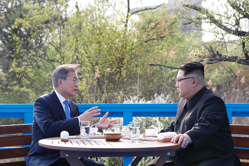 Moon and Kim talk at a table in the demilitarised zone