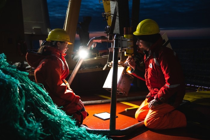 Two researchers with equipment onboard the expedition ship.