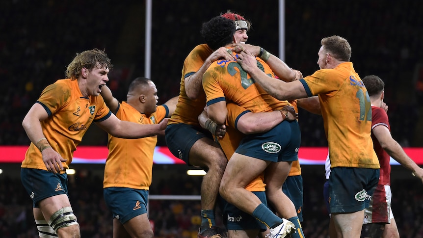 The Wallabies jump and hug each other in celebration
