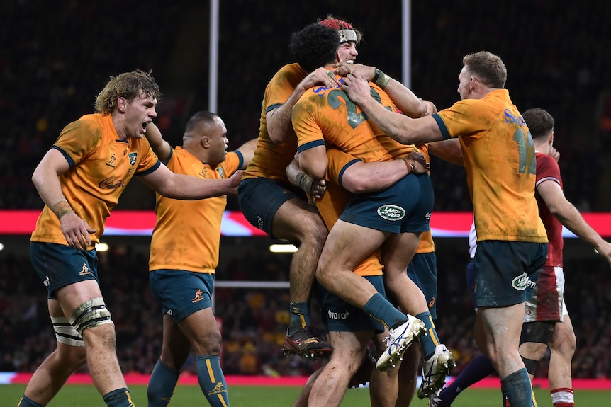 The Wallabies jump and hug each other in celebration