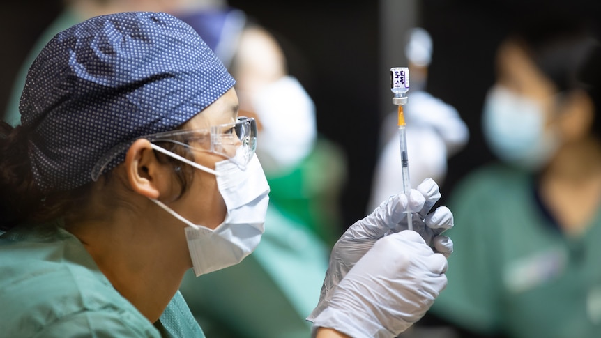 A nurse pulls up a syringe of COVID-19 vaccine.