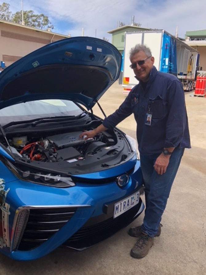 A man with his hand on the motor of a hydrogen-powered car