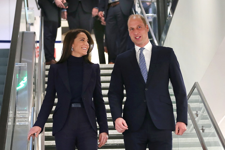 Prince William and Kate descend a set of stairs while chatting 