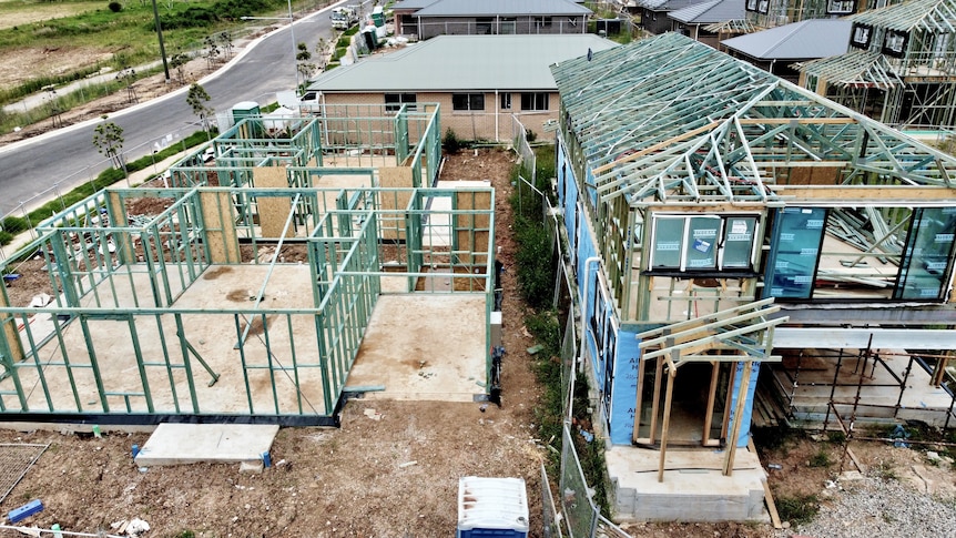 Housing construction seen from above, frames in place but no roof or walls yet.