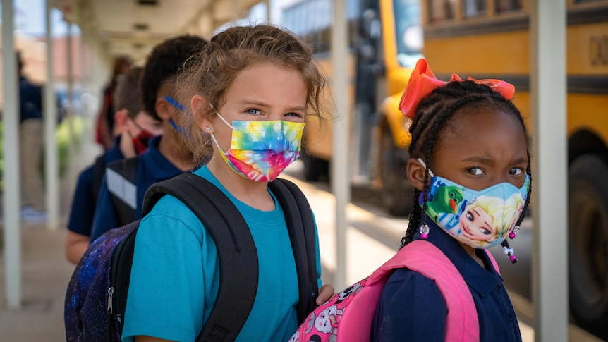 Two little girls in face mask, one tie-dye and the other featuring Elsa from Frozen