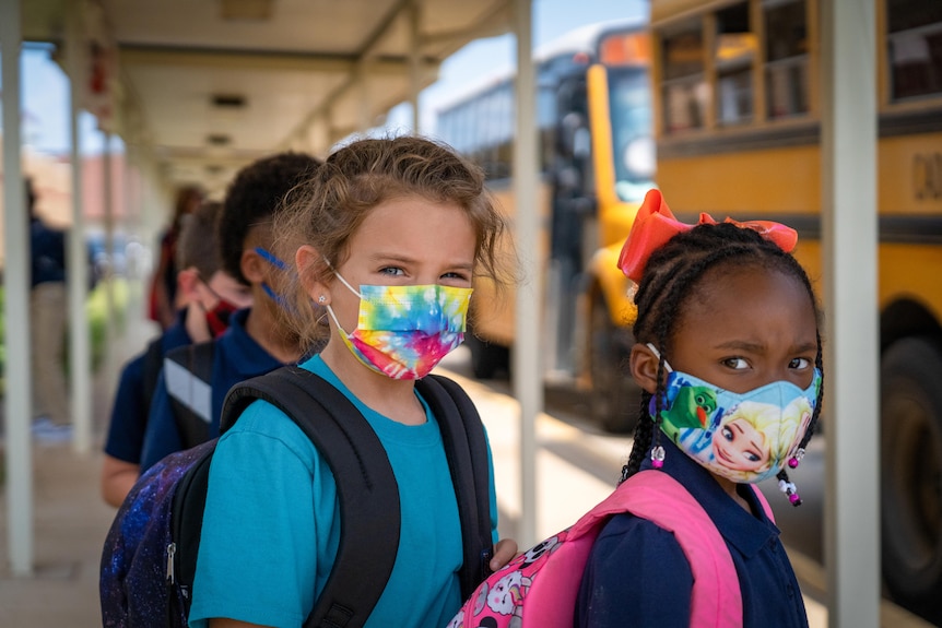 Two little girls in face mask, one tie-dye and the other featuring Elsa from Frozen