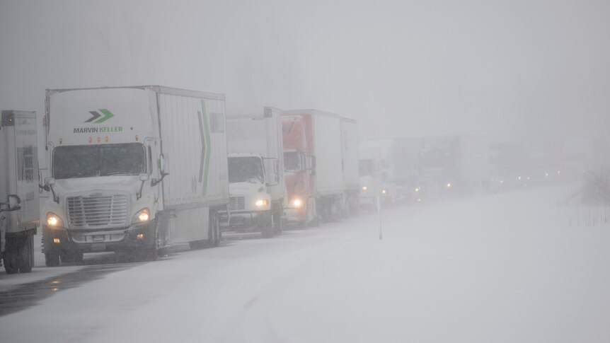 trucks stuck in a traffic jam with snow falling