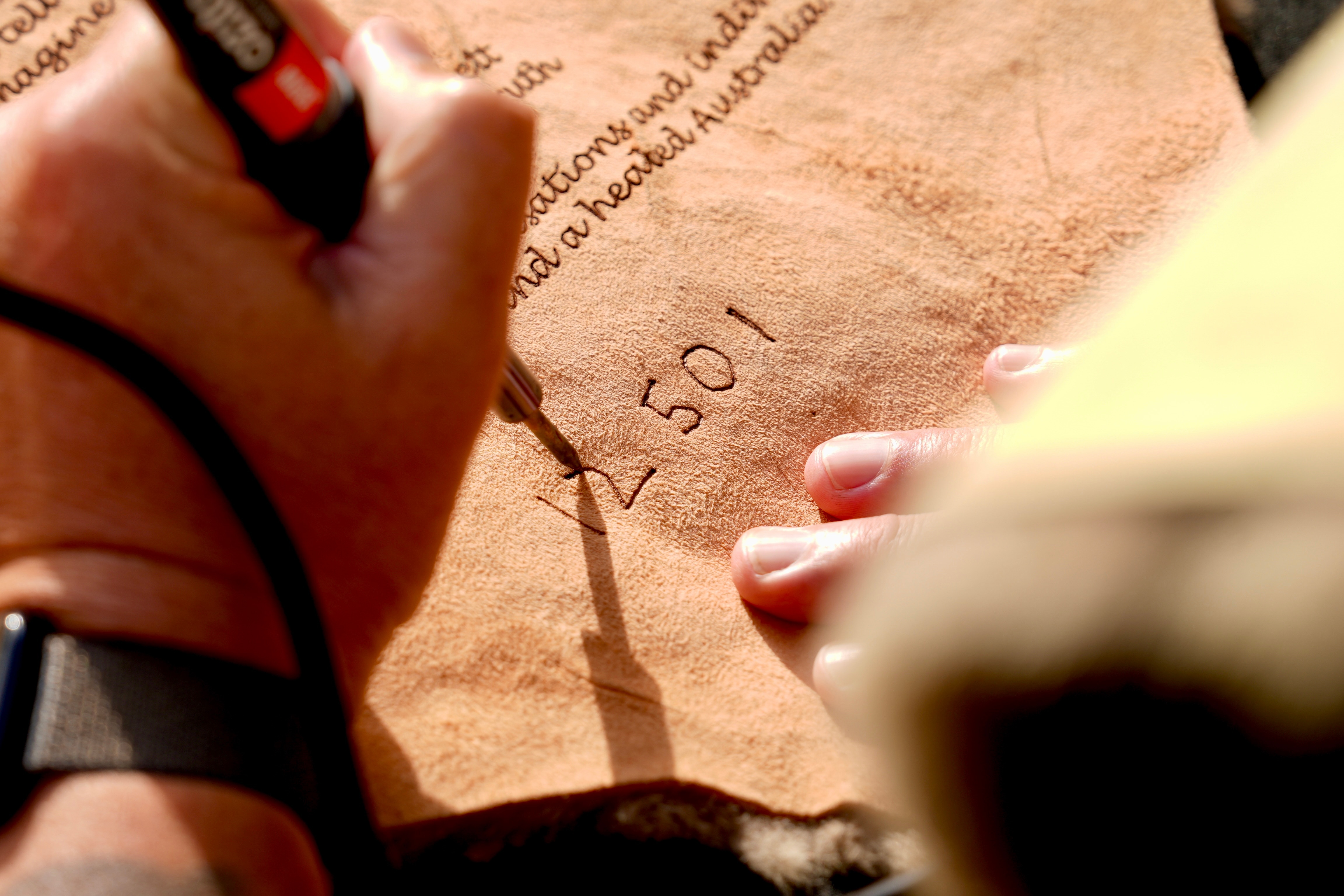 a hand scribing numbers onto kanagaroo cloak