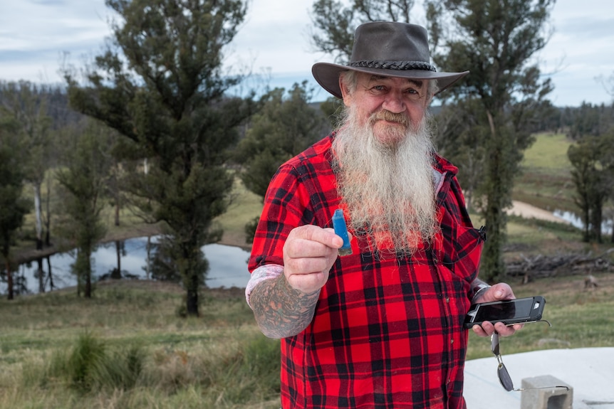 A man with a long white beard holding a blue shotgun shell