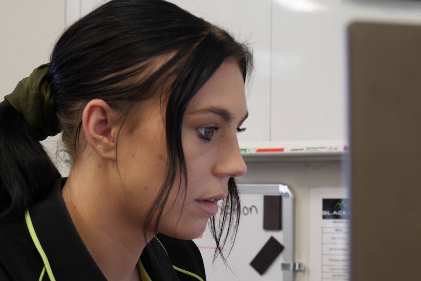 A young woman looks at her computer screen