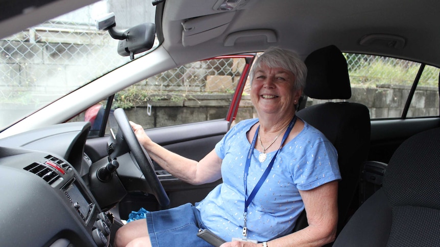 Meals on Wheels volunteer Glad Donnelly posing for a photo in the drivers seat of a car.