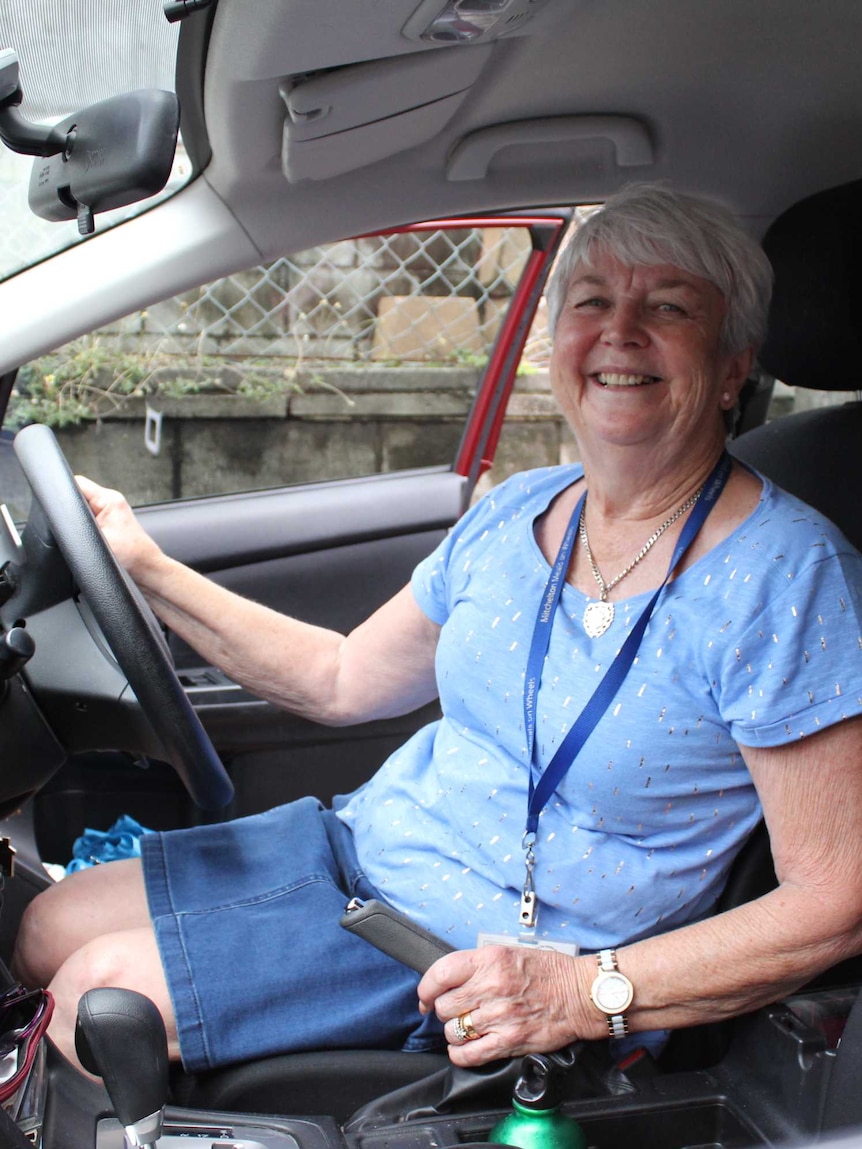 Meals on Wheels volunteer Glad Donnelly posing for a photo in the drivers seat of a car.