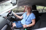Meals on Wheels volunteer Glad Donnelly posing for a photo in the drivers seat of a car.