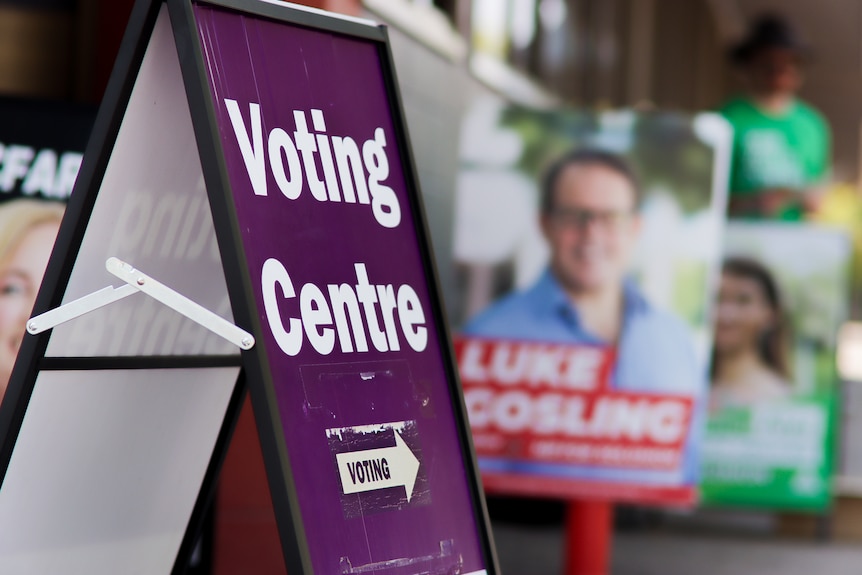 A poster which says 'Voting Centre' with corflutes behind them.