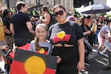 Two people stand with indigenous flag t-shirts in Melbourne.
