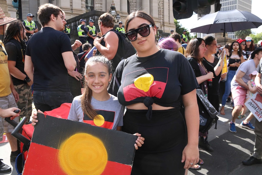 Two people stand with indigenous flag t-shirts in Melbourne.