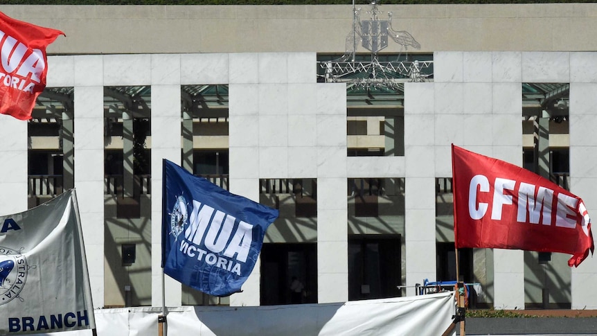 Maritime Union of Australia and Construction, Forestry, Mining and Energy Union flags fly outside Parliament House.