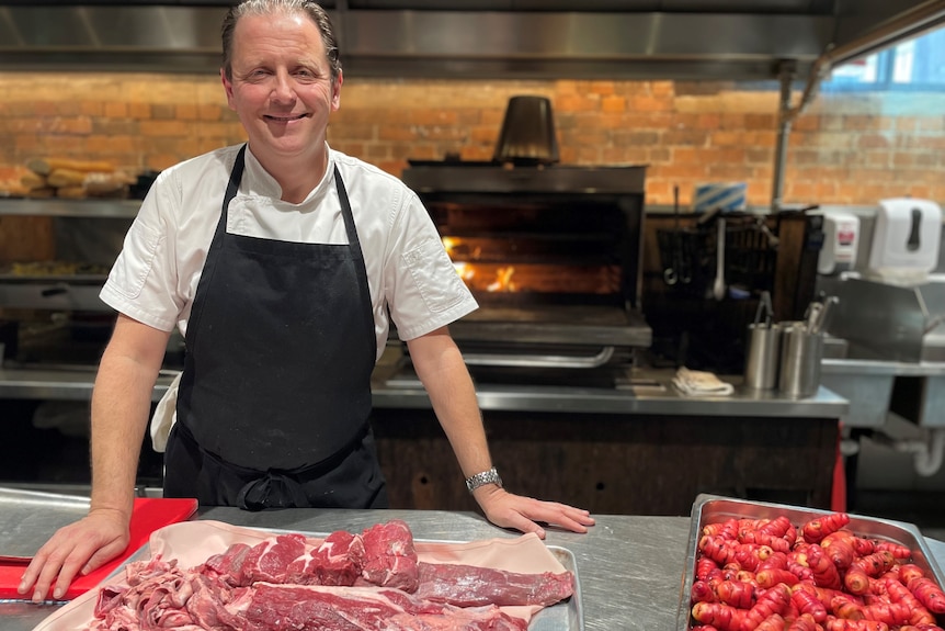Photo of a chef in front of meat.