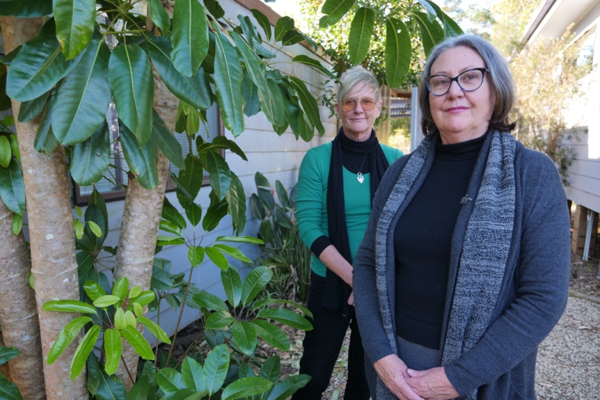 two women stand near plants outside