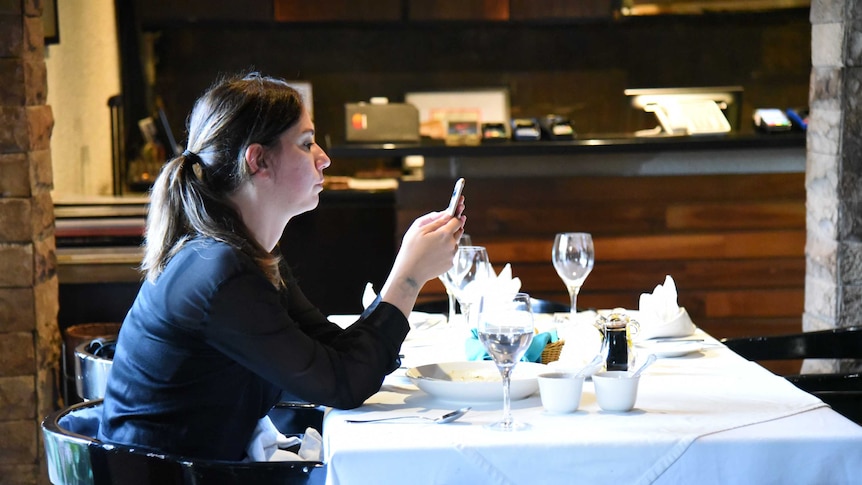 A woman looks at her smart phone in a restaurant
