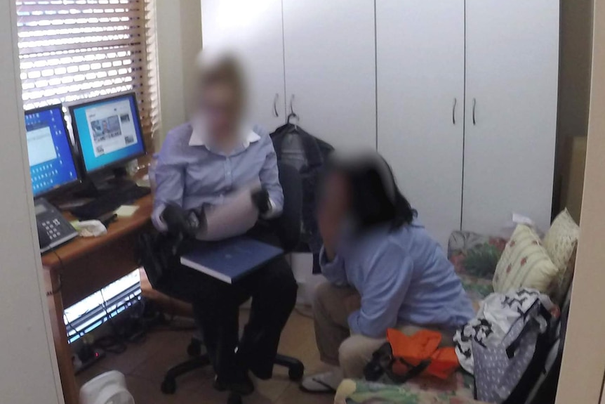 Two people, faces blurred, sitting in a home office