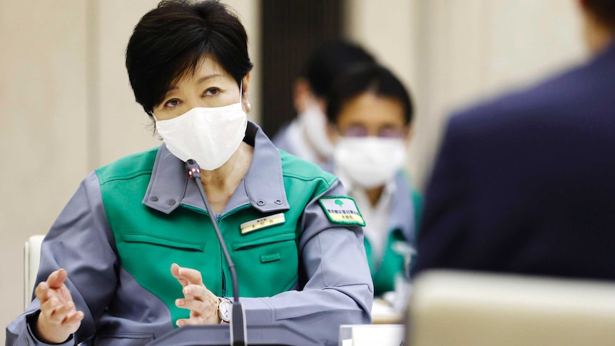 Woman with short dark hair and mask in green uniform