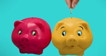 Two piggy banks with a hand feeding a coin into one.