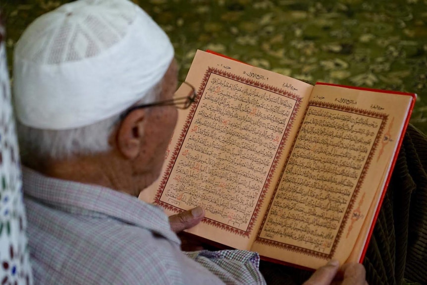 A man reads Islamic script at a mosque.