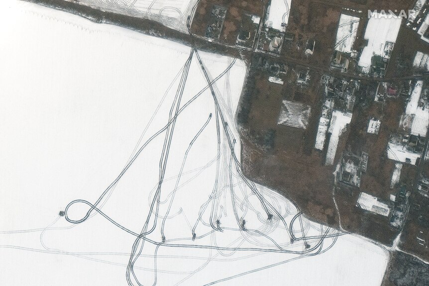 A satellite image showing trails left in snow by armoured vehicles near an airport and series of buildings.