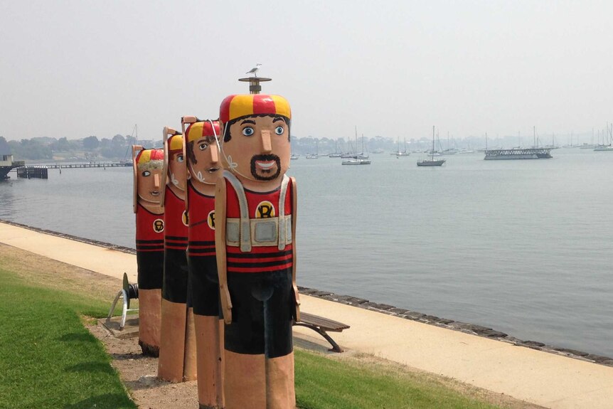 A row of colourful sculptures stand by a Geelong waterfront shrouded in smoke haze.