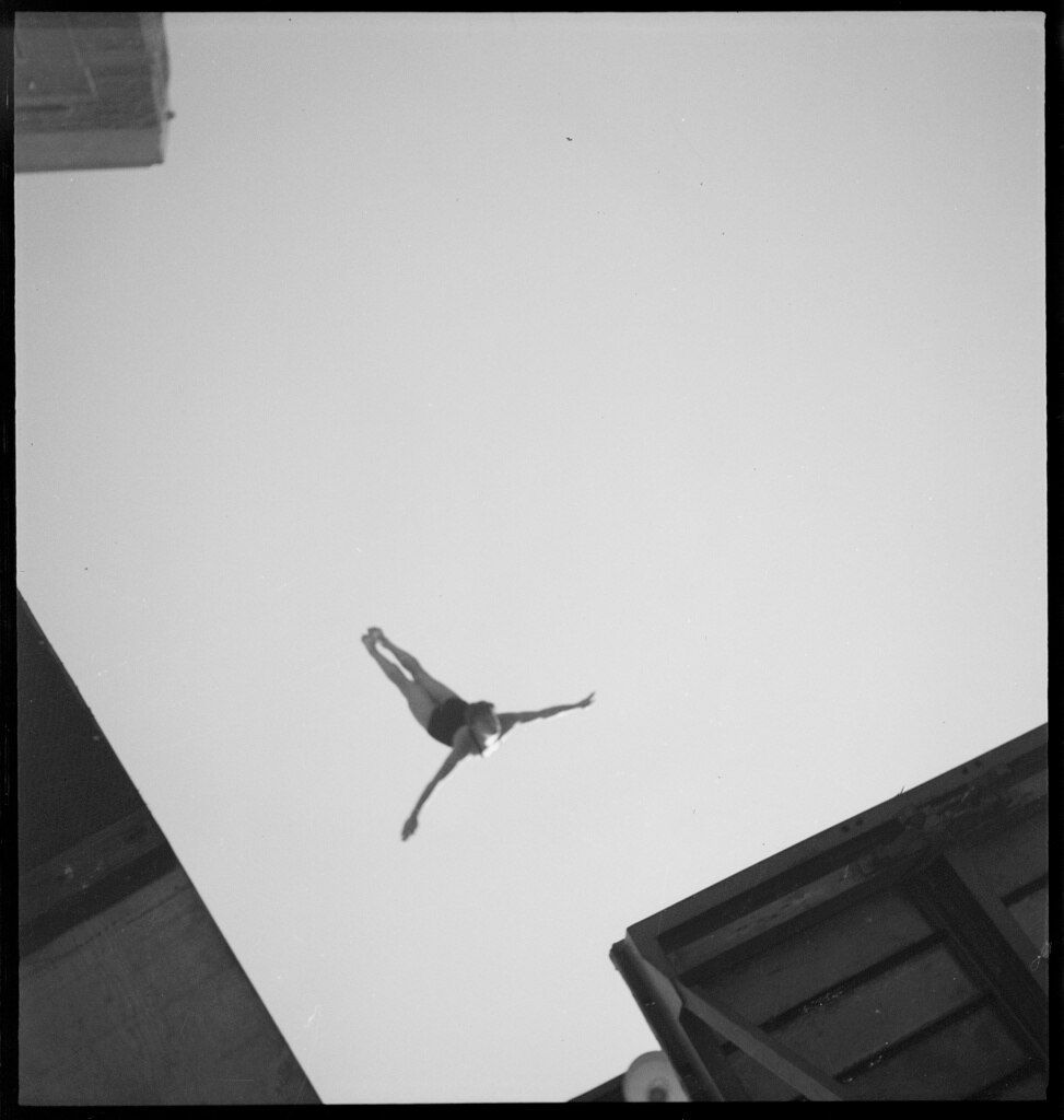 A black and white image taken from below of a person diving